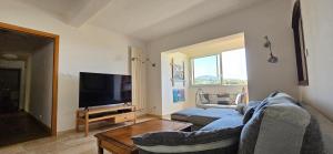 ein Wohnzimmer mit einem blauen Sofa und einem TV in der Unterkunft Villa de standing Les Amandiers, vue mer & piscine in Propriano