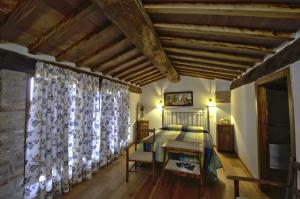 Schlafzimmer mit einem Bett und einem Fenster mit Vorhängen in der Unterkunft Agriturismo Casa del Chiodo in Torniella