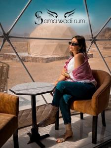 a woman sitting in a chair at a table at Sama Wadi Rum in Wadi Rum