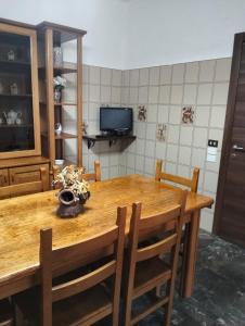 una cucina con tavolo in legno, sedie e TV di Casa Vacanze La Pineta a Taviano