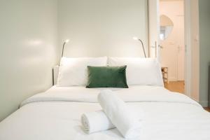 a white bed with a green pillow on it at Cozy apartment near Paris Disney - 6 min from train station in Villiers-sur-Marne