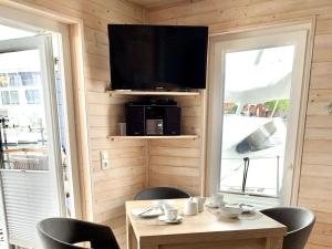 a room with a table with chairs and a television at Houseboat Lasse for family in Heiligenhafen