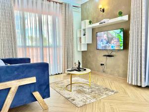 un salon avec un canapé bleu et une télévision dans l'établissement Edenhomes, à Kampala
