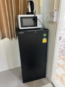 a microwave sitting on top of a refrigerator at Nopphadon Hotel in Lat Krabang