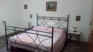una camera da letto con un letto nero con lenzuola rosa di Casa Vacanze La Pineta a Taviano