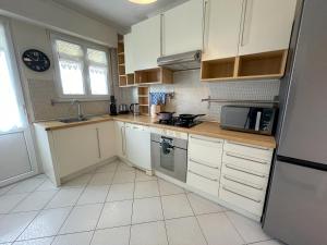 Una cocina con gabinetes blancos y un fregadero. en La Pause Messine - 3 Chambres, en Metz