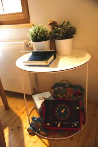 a white table with plants and a clock on it at Charming Chalet with River View in Michelau