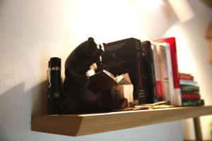a bear statue sitting on a shelf with books at Charming Chalet with River View in Michelau