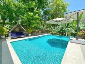 einen Pool mit Sonnenschirm neben einem Haus in der Unterkunft NATURA Loft Garden in Playa Santa Teresa