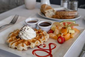 a plate of food with waffles and fruit on a table at Chez Truchon Bistro-Auberge in La Malbaie