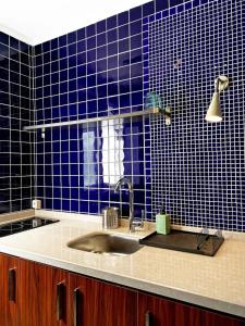 a kitchen with a sink and a blue tiled wall at Petek Pansiyon Fenerbahce Kadikoy in Istanbul
