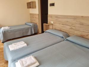 Dos camas en una habitación con toallas. en Hostal O Patron, en Santiago de Compostela