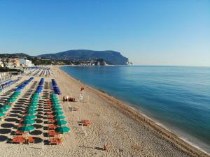 a beach with chairs and umbrellas and the ocean at Il granchio in Marcelli
