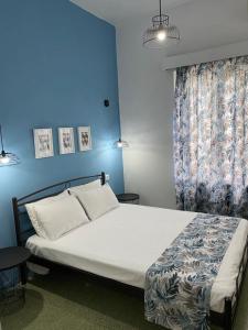 a bedroom with a white bed with a blue wall at Thalia Hotel in Kamena Vourla