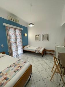 a bedroom with two beds and a table and chairs at Thalia Hotel in Kamena Vourla