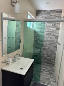 uma casa de banho com um lavatório e um chuveiro com um espelho. em Casa 112 Residencial Framboyanes em Santa Cruz Xoxocotlán