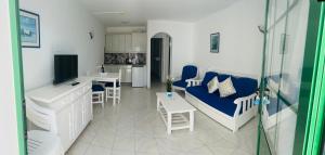 a living room with a blue couch and a kitchen at -MONTORIAN Apartments -LANZAROTE in Tías