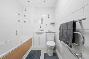 a white bathroom with a toilet and a bath tub at Modern 2Bed Northern Quarter, Long Stays, Contractors in Manchester