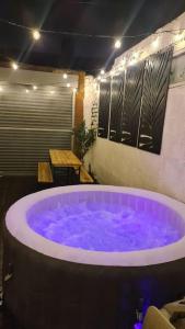 Cette chambre comprend une grande baignoire pourpre et une table. dans l'établissement Cabin of Light - Hot Tub, Sauna, Massage Chair, BBQ, Games, Beach, à Monkwearmouth