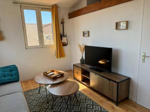 ein Wohnzimmer mit einem TV und einem Tisch in der Unterkunft ღ L'Entr'Act • Au cœur de ville et du vieux Port in La Rochelle