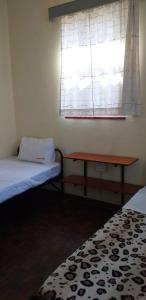 a room with two beds and a table and a window at 4-Bedroom Apartment in Pretoria