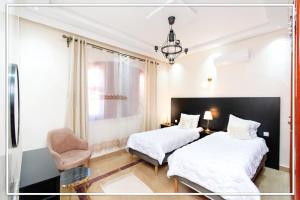 2 camas en una habitación de hotel con silla en RIAD TARGA - Marrakech, en Marrakech