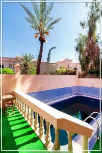 a balcony with a pool and a palm tree at RIAD TARGA - Marrakech in Marrakech