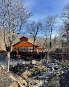 a wooden cabin with a bridge over a river at Cozy Cabin Walkable to Beech Mt Resort in Beech Mountain