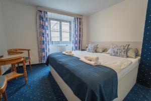 a bedroom with a bed with a table and a window at Hotel Gabreta in Sušice