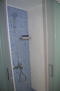 W łazience znajduje się prysznic i niebieska ściana wyłożona kafelkami. w obiekcie CHORA HOUSE KYTHNOS w mieście Kitnos