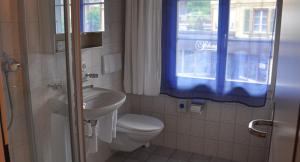 La salle de bains est pourvue de toilettes, d'un lavabo et d'une fenêtre. dans l'établissement Hotel Krone Uetendorf, à Uetendorf