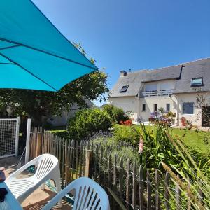 a patio with chairs and an umbrella and a house at Gites des menhirs in Camaret-sur-Mer