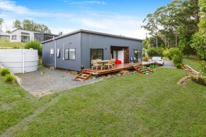 a gray house with a picnic table in a yard at Tranquil Countryside Retreat with Modern Amenities in Pokeno