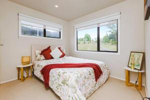 um quarto com uma cama e duas janelas em Tranquil Countryside Retreat with Modern Amenities em Pokeno