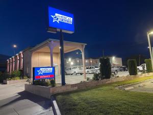 un cartel en frente de un estacionamiento por la noche en Americas Best Value Inn-Mojave en Mojave