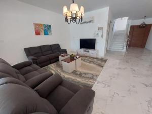 a living room with a couch and a tv at Hacienda bay villa in Sīdī ‘Abd ar Raḩmān