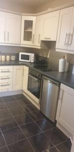 cocina con armarios blancos y encimera negra en Town Centre Apartment en Trim