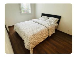una camera da letto con un letto con un piumone e cuscini di Chambre spacieuse et lumineuse a Nanterre