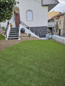 une maison avec des escaliers et une cour herbeuse dans l'établissement Casa da Fonte, à Seia