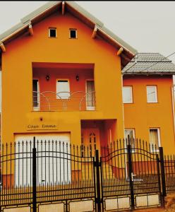 ein orangenes Haus mit einem Zaun davor in der Unterkunft Casa Emma in Vişeu de Jos