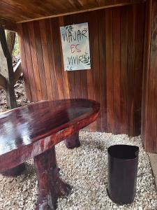 un banco de madera sentado frente a una pared de madera en Refugio del Bosque CABAÑAS Y GLAMPING, en Guácimo