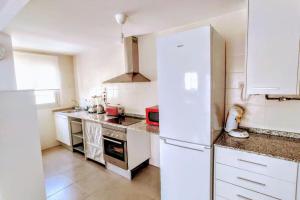 cocina con armarios blancos y nevera blanca en Apartamento nuevo en el centro de Gandía, en Gandía