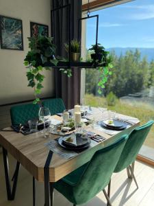 una mesa de madera con sillas verdes y una ventana en LOFT MOUNTAIN Apartament Szklarska Poręba, en Szklarska Poręba