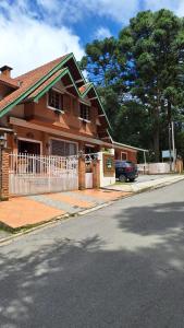 a brown house with a white fence on a street at Pousada Atalaia Capivari in Campos do Jordão