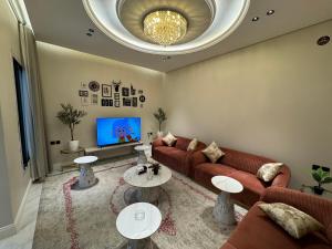 a living room with a couch and tables and a tv at شقة غرفة وصالة وجلسة خارجية بالعارض ٨ in Riyadh
