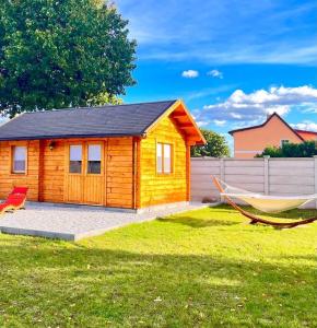 a small wooden cabin with a hammock in a yard at Glückseligkeit am Waldesrand 