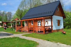 uma pequena casa com um parque infantil e um baloiço em Niesamowita Dolina 