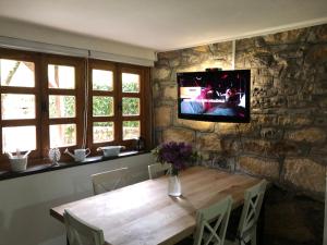a dining room table with a television on a stone wall at Kuća Mitića in Pirot