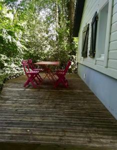 2 rote Stühle und ein Tisch auf einer Veranda in der Unterkunft Gîte vallée du denacre entre terre et mer in Wimille