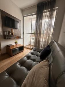 uma sala de estar com um sofá de couro e uma grande janela em Apartamento en la mejor zona de sabaneta em Sabaneta